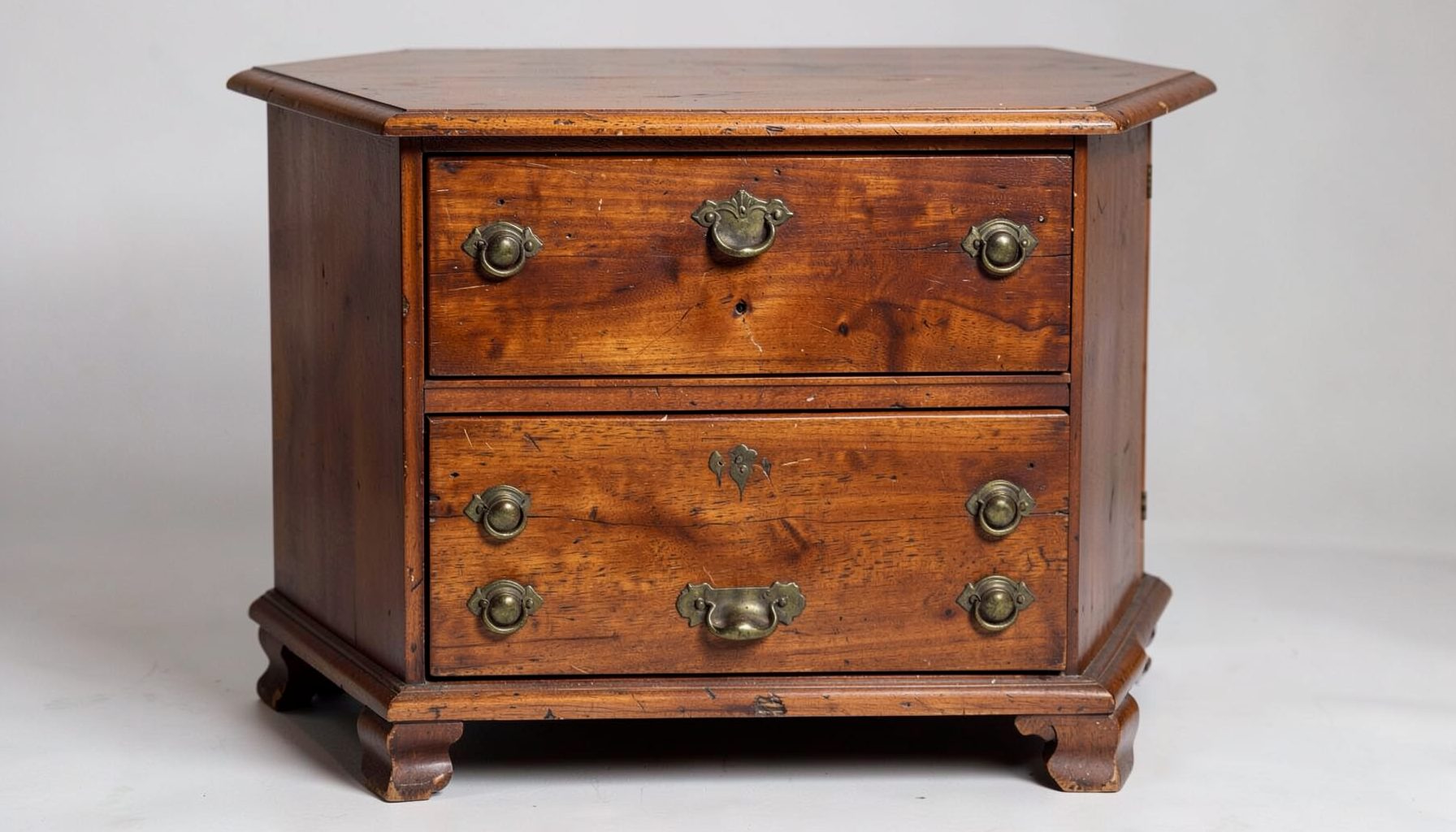 Antique wooden chest of drawers with brass hardware, rich patina and warm brown tones, classic American design