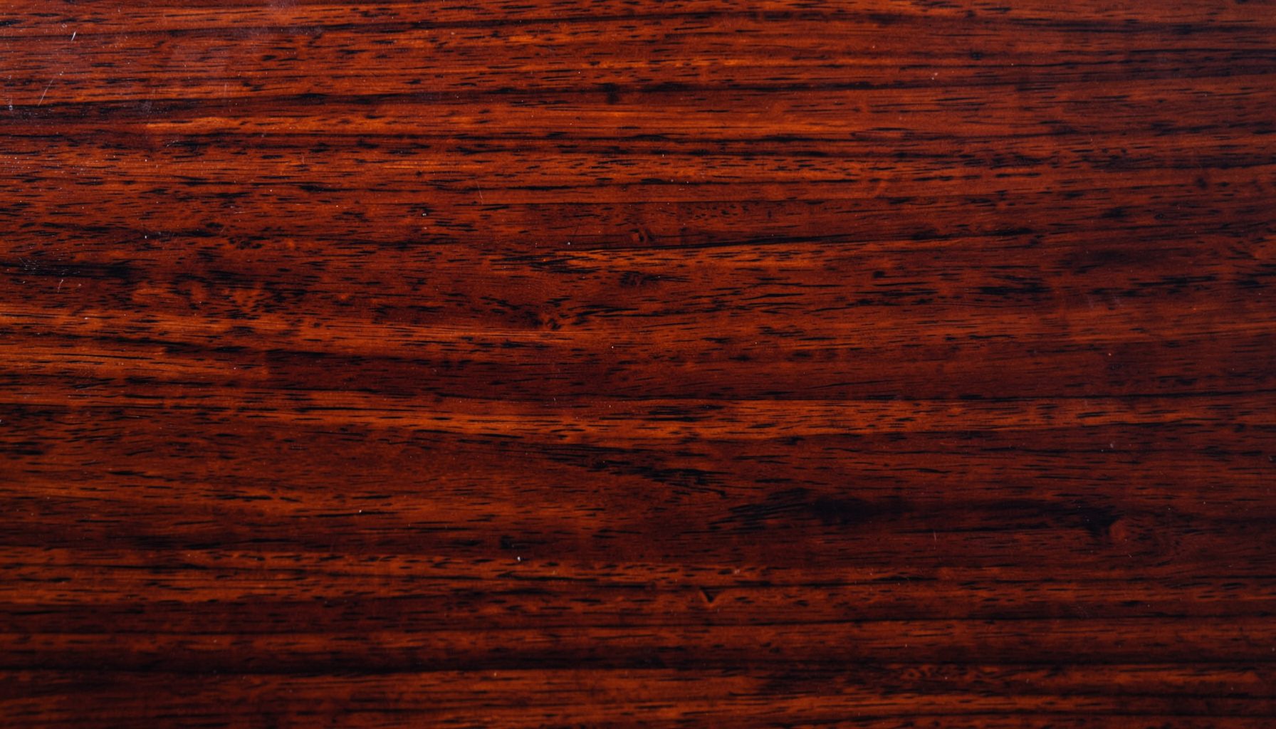 Rich mahogany wood surface with deep reddish-brown grain and a subtle gloss, warm and elegant