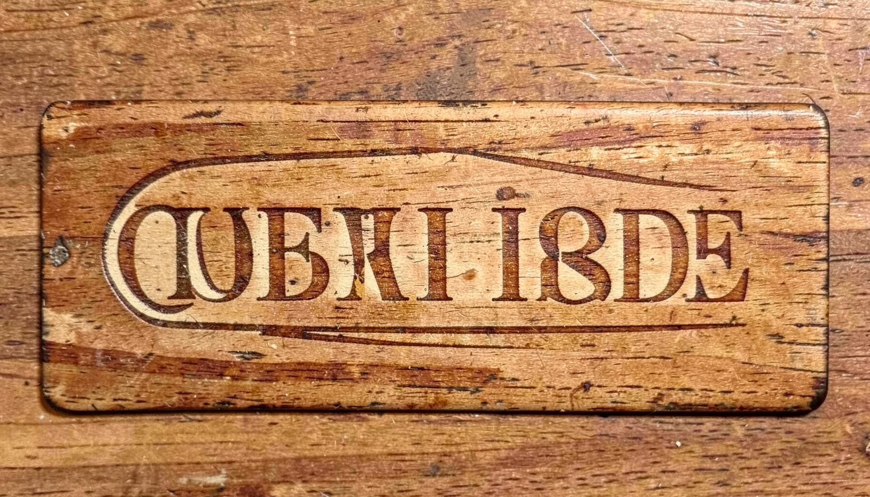Vintage wooden furniture label with classic serif typography in warm brown and cream tones